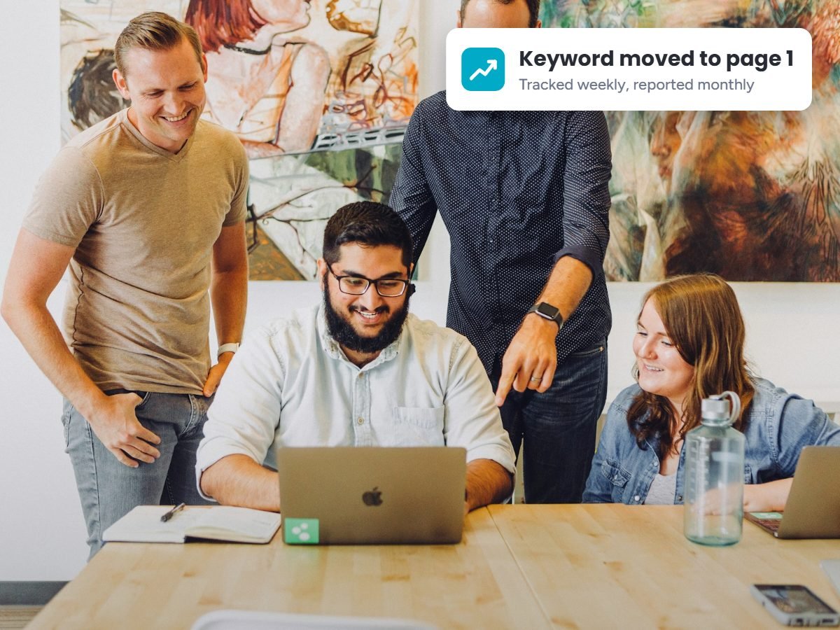 SEO specialists reviewing keyword ranking progress on a laptop